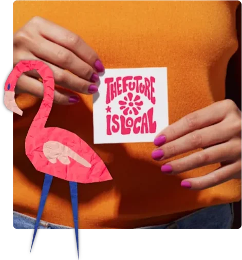 A pana holding a “The Future Is Local” sticker beside a paper flamingo